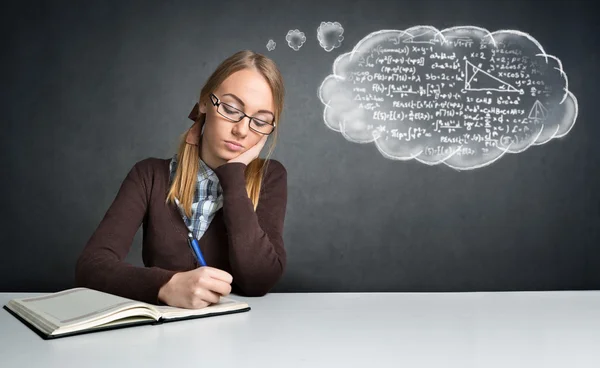 Denkende Studentin am Schreibtisch Stockbild