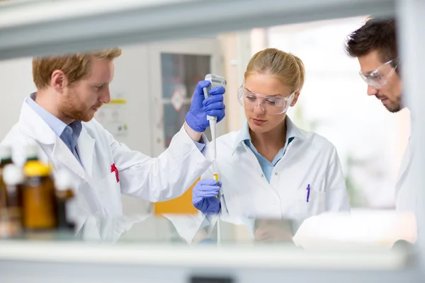 Skupina chemické vědci místo vzorku tekutiny v testování pipet — Stock fotografie