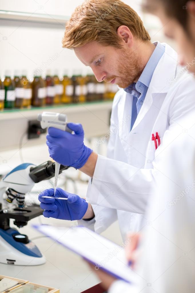 Male chemical scientist place sample of liquid on microscope sli