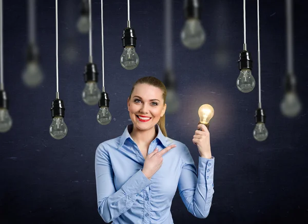 Smiling girl holding a light bulb shining — Stock Photo, Image