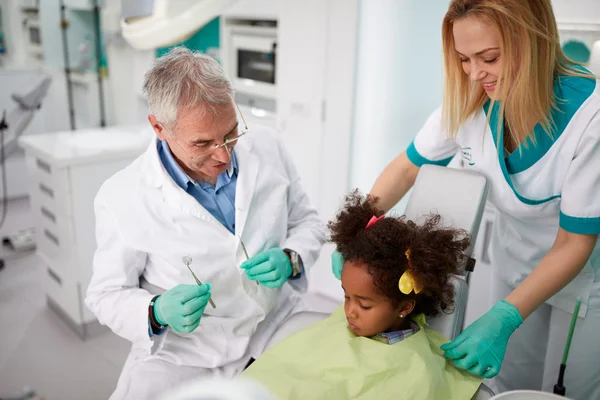Zahnarzt und seine Assistentin trösten kleines Mädchen — Stockfoto