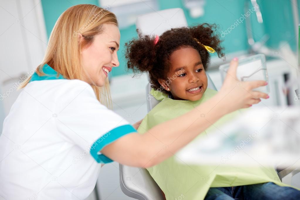 Dental assistant shows repaired teeth to little girl