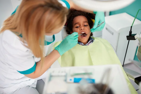 Жіночий стоматолог відновлює зуб приємному чорному хлопчику — стокове фото