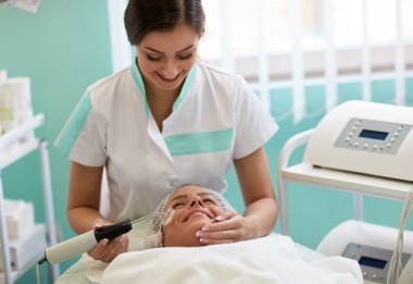 Neşeli genç kız güzellik uzmanı tarafından yüz tedavi görüyor