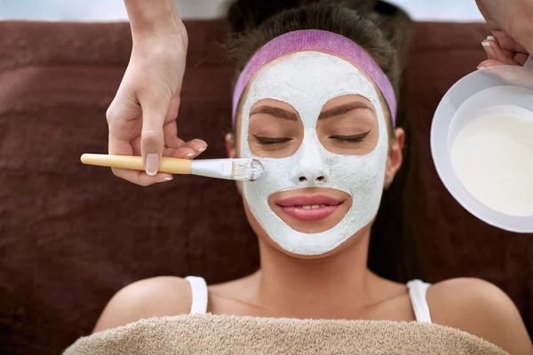 Schoonheidsspecialist gezichts masker op het gezicht van de vrouw toe te passen — Stockfoto