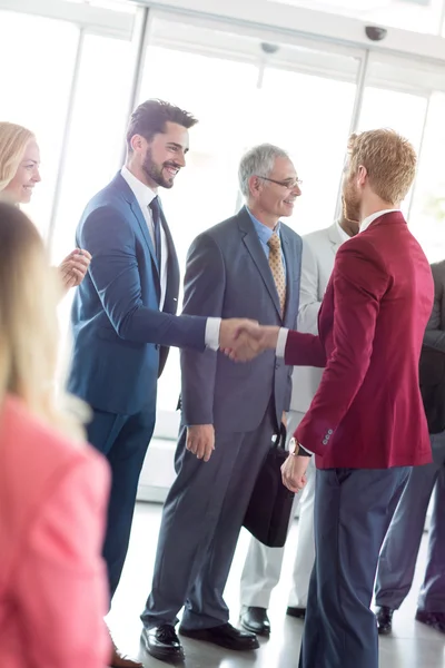 Pasangan bisnis tersenyum berjabat tangan dengan leade — Stok Foto