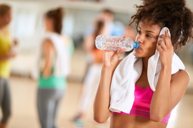 Thirsty girl after body training drink water and wipes sweat clipart