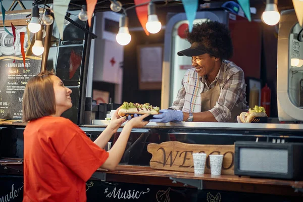 Молодой Кавказский Довольный Клиент Принимает Заказы Сэндвичи Веселого Афро Американского — стоковое фото