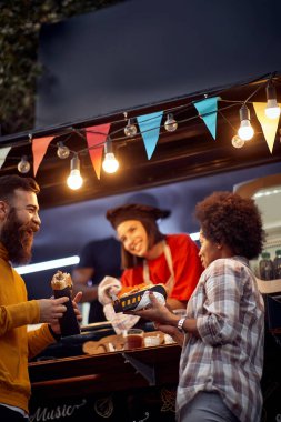 Çok ırklı bir çiftin dışarıda fast food eşyasının önünde güzel vakit geçirdiği, sohbet ettiği ve sandviç yediği çeşitli görüntüler.