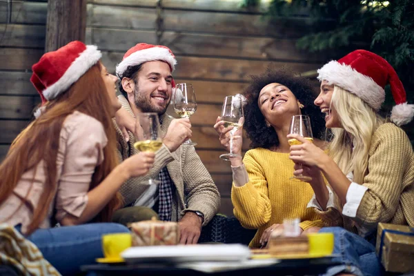一緒にお祝いの雰囲気の中でクリスマスや新年のパーティーでチャットやお酒を若い陽気な人々のグループ Xmas トースト 楽しい パーティーのコンセプト — ストック写真