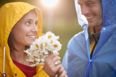 Bir erkeğin çiçek buketini alan bir kadının portresi, yağmurlu bir günde aşk.