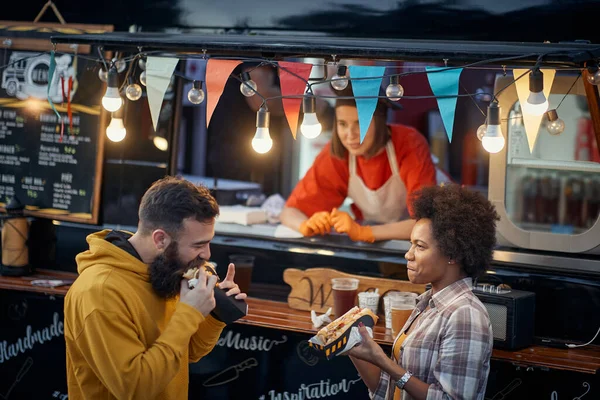 Pareja Multiétnica Comiendo Sándwiches Frente Servicio Comida Rápida Exterior —  Fotos de Stock