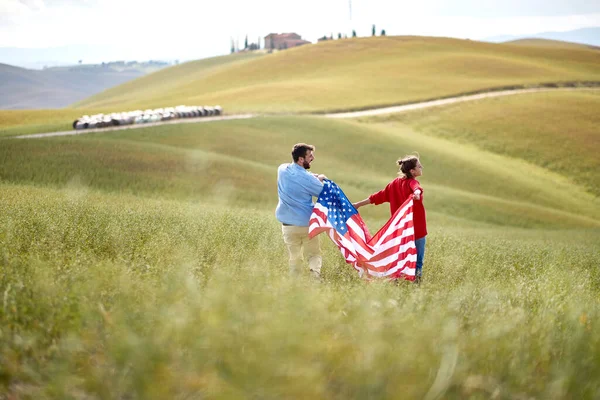 사랑하는 커플이 아름다운 초원에서 국기를 있습니다 — 스톡 사진