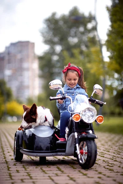 Gelukkig Klein Meisje Rijden Een Speelgoed Motorfiets Met Haar Hond — Stockfoto