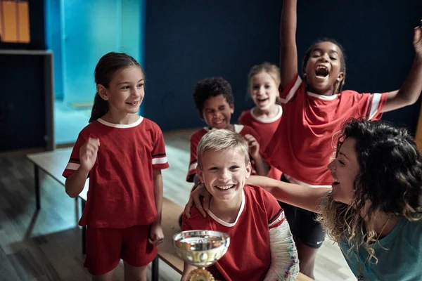 Kinderteam Vrouwelijke Coach Kleedkamer Poseren Met Een Gewonnen Trofee Kinderteamsport — Stockfoto