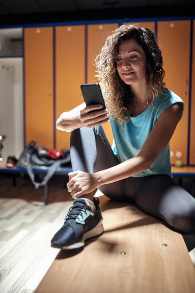 フィットネストレーニングを待っている間 スマートフォンでテキストメッセージを送るロッカールームの若いハンサムな女の子 レクリエーション フィットネス スポーツ — ストック写真