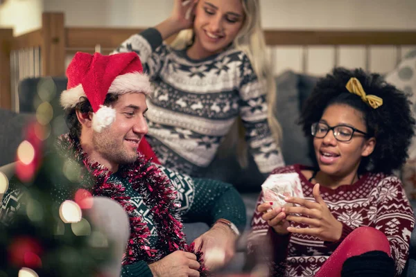 サンタの帽子の友人のグループ一緒にクリスマスの贈り物を交換する ホームクリスマスのお祝いのコンセプト — ストック写真