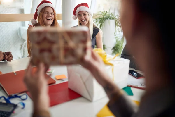 Collega Mostrando Regalo Avvolto Due Colleghe Donne Ufficio Con Cappelli — Foto Stock