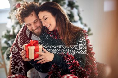 Evde Noel sabahı hediyeleri paylaşan romantik çift; Beyaz Noel konsepti