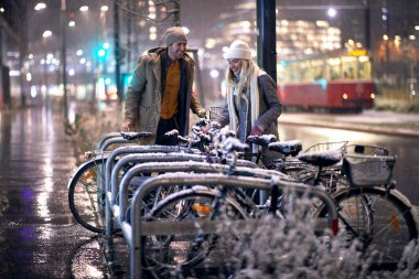 Genç beyaz çift karlı havada bisiklete binmek üzere.