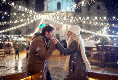 Genç bir çift, şehrin soğuk ve karlı havasında büyülü bir gecede güzel bir Noel festivalinde ısınıyor. Festival, aşk, ilişki, Xmas, kar