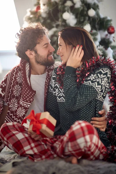 陽気なカップル共有ギフト上のクリスマスの朝に自宅 — ストック写真