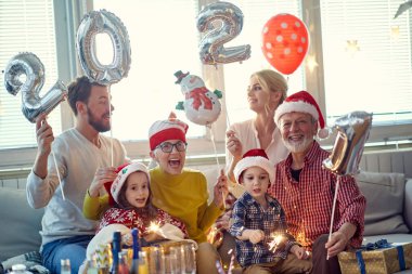 Mutlu aile, Noel arifesi ev partisinde festival atmosferinde fotoğraf çektirmek için poz veriyor. Yılbaşı, tatil, ailecek vakit geçirmek.