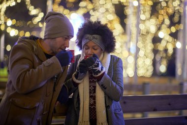 Genç bir çift güzel bir gecede buz pateni sahasında çayla ısınıyor. Kayak, yakınlık, aşk, birlikte