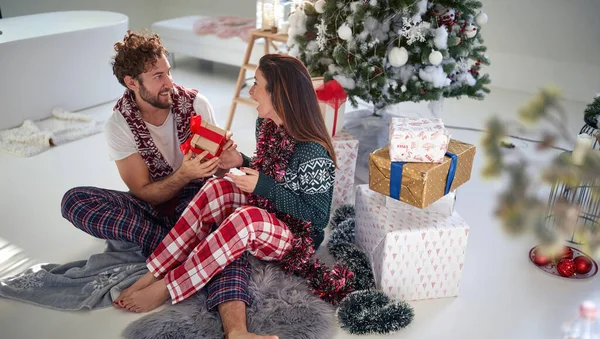 クリスマスを楽しんでいる若いカップルは 自宅で美しい休日の朝にプレゼントします クリスマス 一緒に — ストック写真