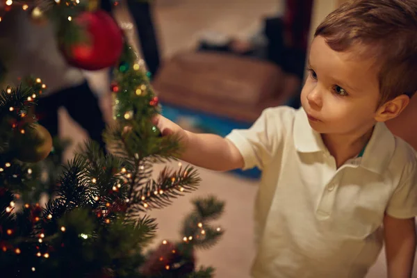 Menino Bonito Assistindo Ornamentos Uma Árvore Natal Uma Atmosfera Férias — Fotografia de Stock