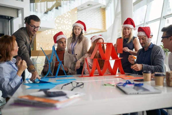 Коллеги Ярком Офисе Веселятся Рождество Строят Бумажные Башни Работе — стоковое фото