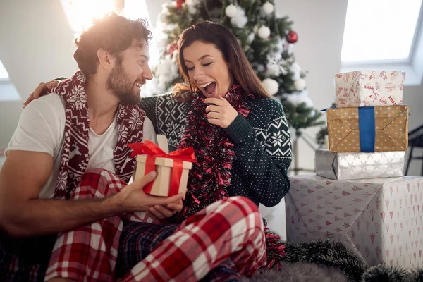 Genç bir çift, güzel bir bayram sabahı etrafı Noel hediyeleriyle çevrili yerde oturuyor. Noel, ilişki, aşk, birlikte