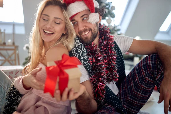 Evinde güzel bir tatil sabahında kız arkadaşına Noel hediyesi veren bir adam. Noel, ilişki, aşk, birlikte