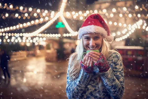 Karlı bir kış gecesinde dışarıda kahve içen bir kadının portresi.