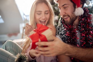 Sakallı adam Noel 'de kız arkadaşına hediye veriyor. Kafasında Noel Baba şapkasıyla, gülümsüyor. Noel konsepti