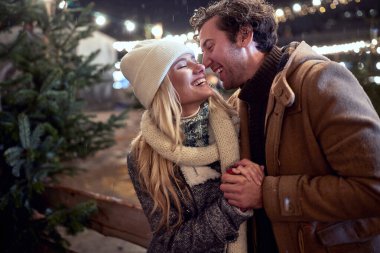 Mutlu çift bir kış gecesinde Noel ağacını yudumluyor.