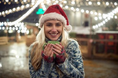 Karlı bir kış gecesinde dışarıda kahve içen bir kadının portresi.