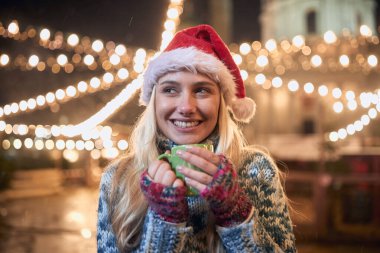 Karlı bir kış gecesinde dışarıda çay içen bir kadının portresi.