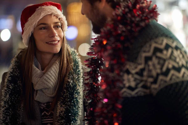 A young couple in lovely Xmas moments while walking the city together on a beautiful holiday night. Christmas, relationship, love