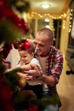 Mutlu baba ve oğul evde birlikte Noel ağacı süslüyorlar.