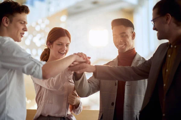 A group of employees building up spirit of togetherness in a pleasant atmosphere at company hallway. People, job, company, business concept.