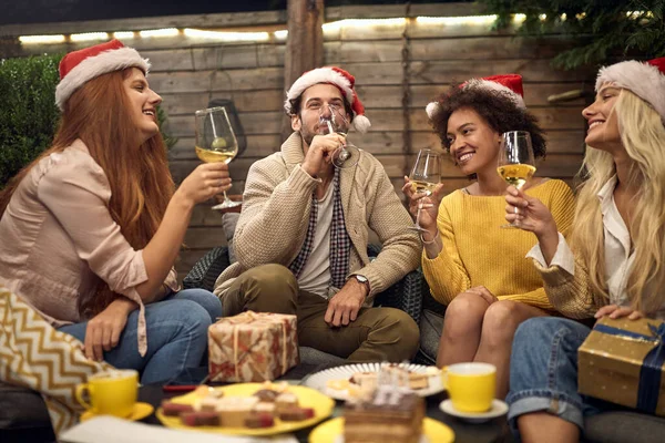 サンタの帽子をかぶって新年を祝う白ワインを飲む若い大人のグループ — ストック写真