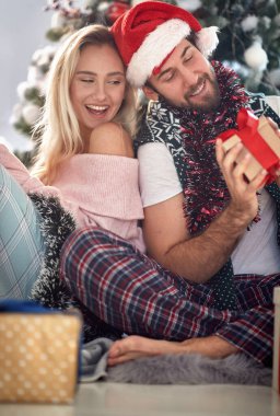 Mutlu bir çiftin evde Noel sabahı hediyelerini paylaşması; Beyaz Noel konsepti