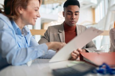 Şirket kantinindeki hoş bir atmosferde dokümanların içinden geçen genç meslektaşlar. İnsanlar, iş, şirket, iş kavramı.