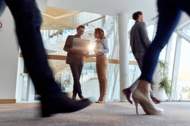 Genç meslektaşlar, şirketin koridorunda neşeli bir atmosferde görevler hakkında konuşuyorlar. İnsanlar, iş, şirket, iş kavramı.