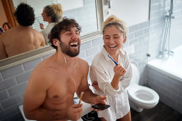 在浴室里一个美丽的早晨 年轻夫妇一边刷牙一边谈情说爱 — 图库照片