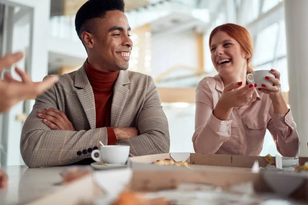 休憩時間にコーヒーを楽しみながら会社の食堂で陽気な雰囲気の中でおしゃべりをする従業員のグループ ビジネスコンセプト — ストック写真