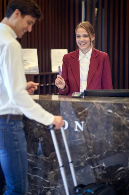 Güzel bayan resepsiyonist kibarca ve gülümseyerek oteldeki misafirden verileri alıyor. Turizm, iş, otel