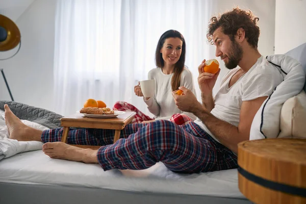 ベッドルームで朝食をとるためのおいしい食べ物を持っている若いカップル 一緒に — ストック写真