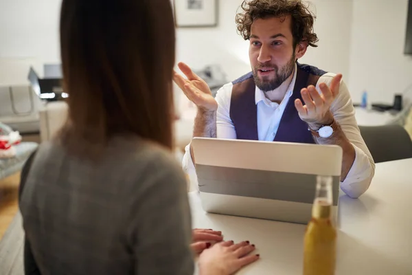 A young handsome businessman in a relaxed atmosphere at his home office questioning a young sexy girl during an interview for a job. Business, interview, people